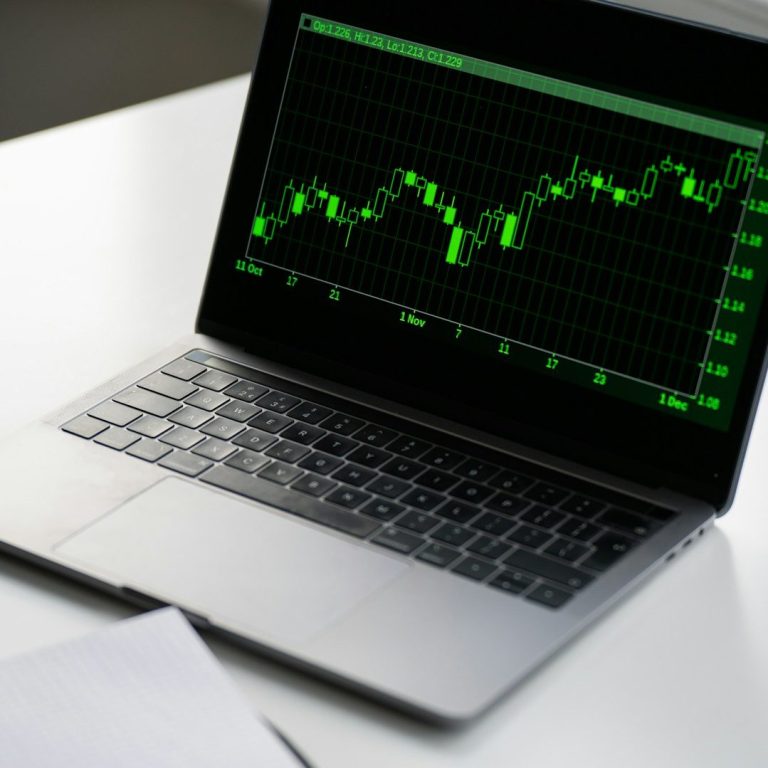 Laptop screen showing green profitable crypto trading chart graph